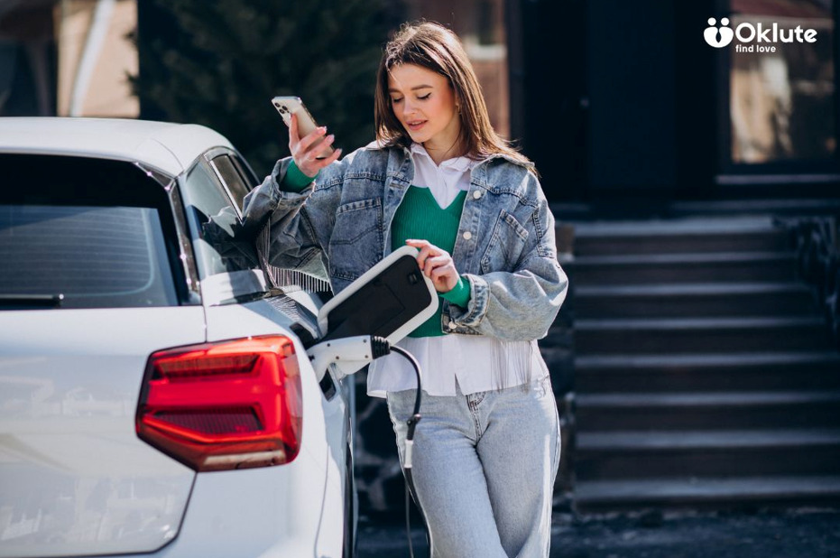 Electric Vehicles vs. Hybrid Vehicles: Which Is Better for Your Driving Needs? Woman charging an electric vehicle while checking her phone